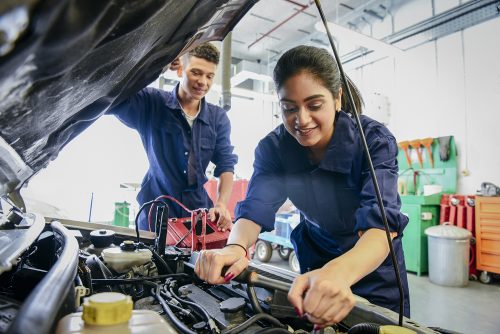 Automotive apprentices repairing vehicle