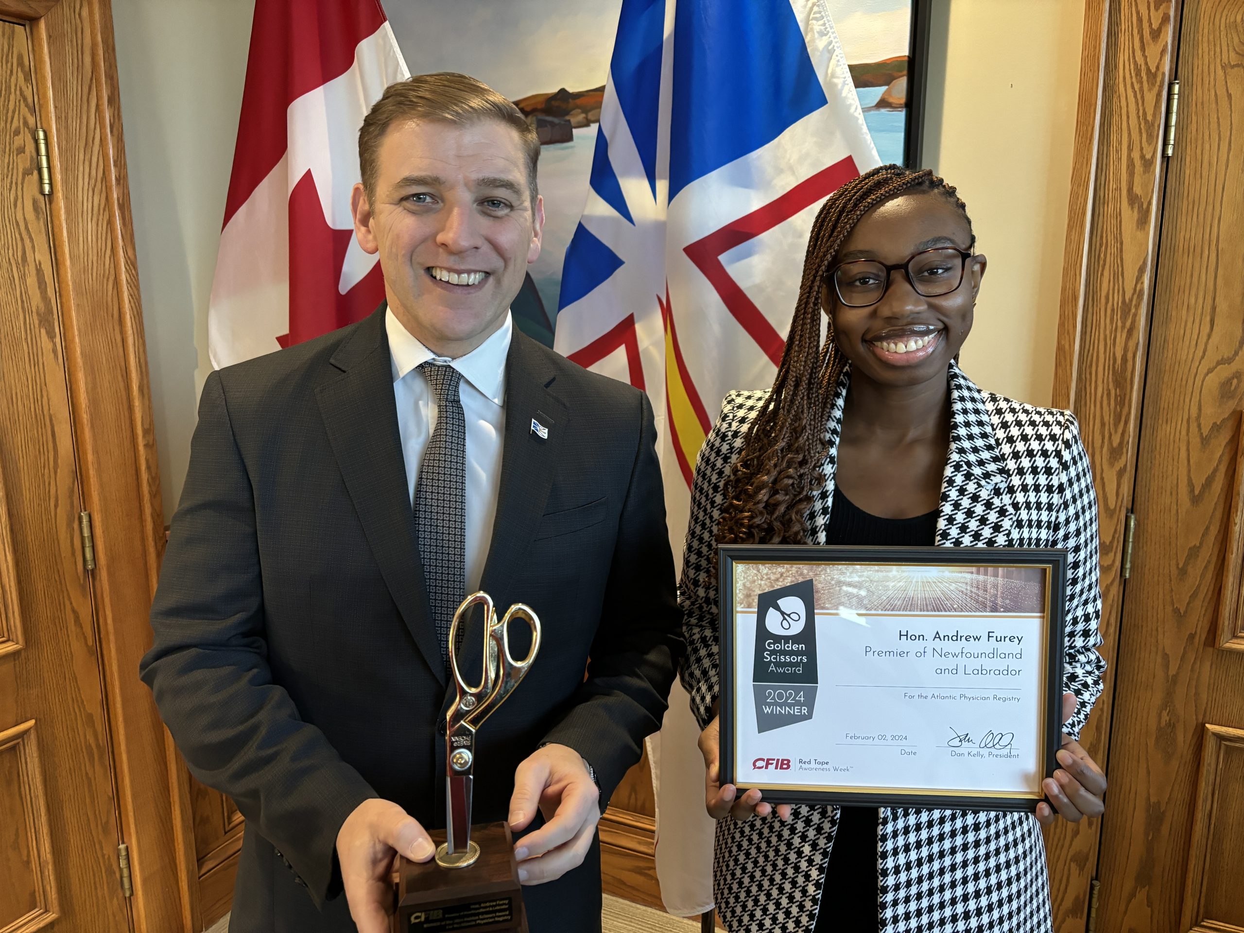 Premier Furey accepts the Golden Scissors Award from Beatrix Abdul Azeez, CFIB Policy Analyst, in his office in St. John’s, N.L. 